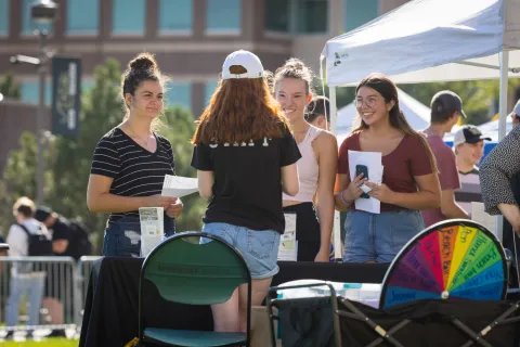 Image of a club fair. People gather around a table talking.