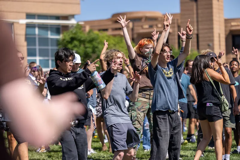 A group of students cheering with their hands raised.